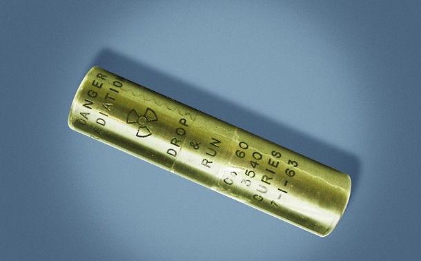 A metal cylinder with pressed letters saying “DANGER RADIATION ☢ DROP & RUN Co 60 3540 CURIES 7-1-63”